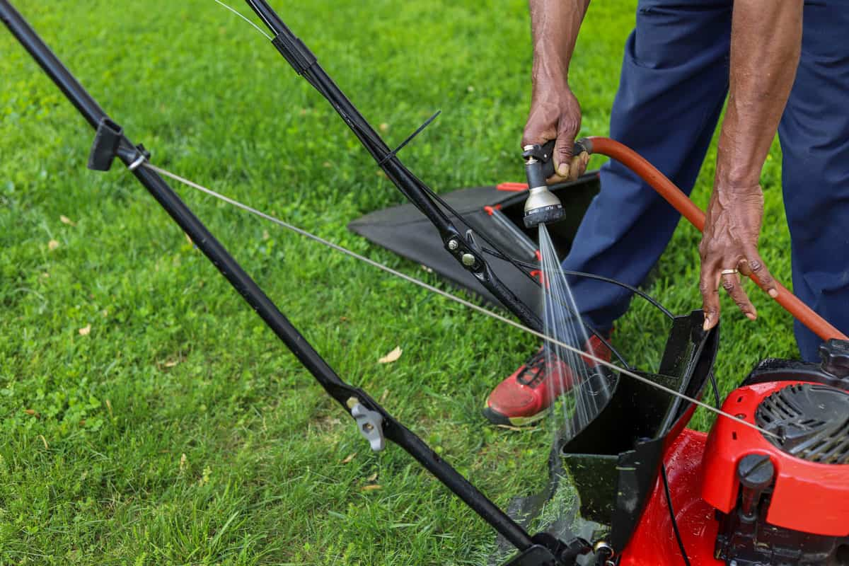 person cleaning lower mower with water