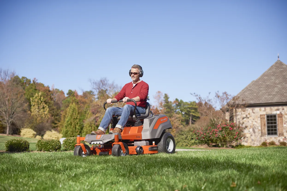 person wearing red shirt riding orange lawn mower